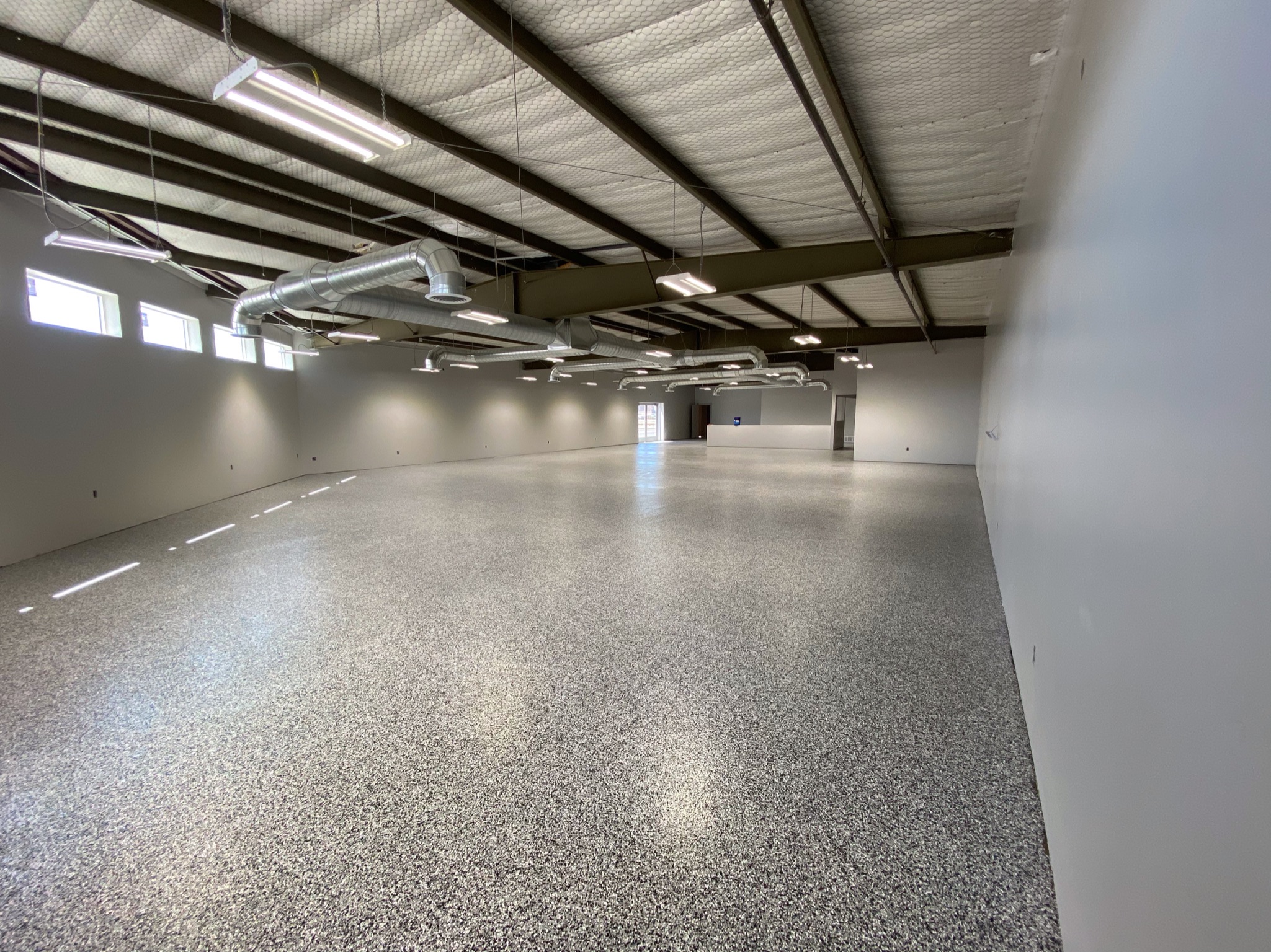 Large commercial space with full-broadcast gray flake floor coating - Sparks Coatings