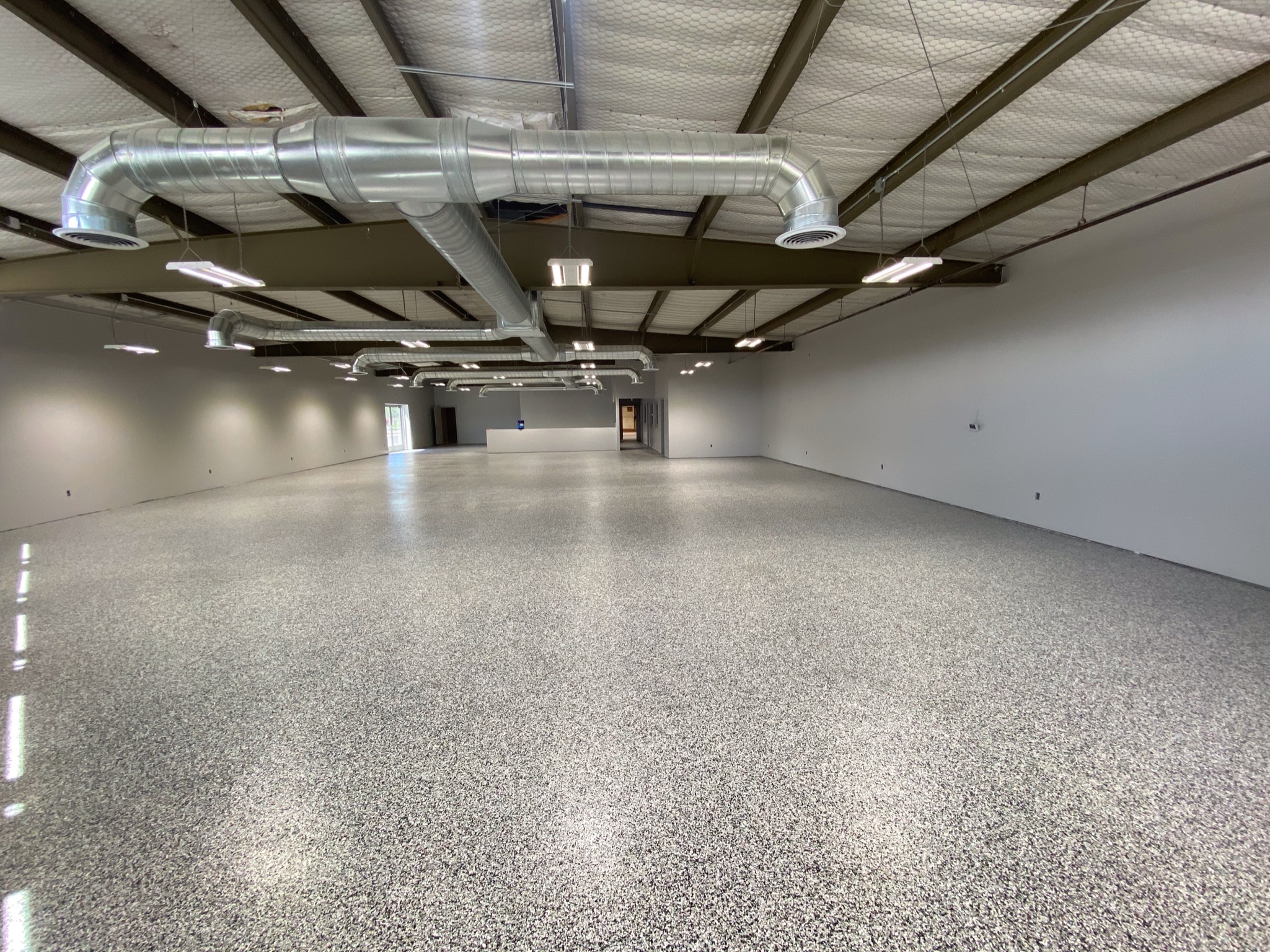 Wide commercial building floor with gray full-broadcast professional coating - Sparks Coatings