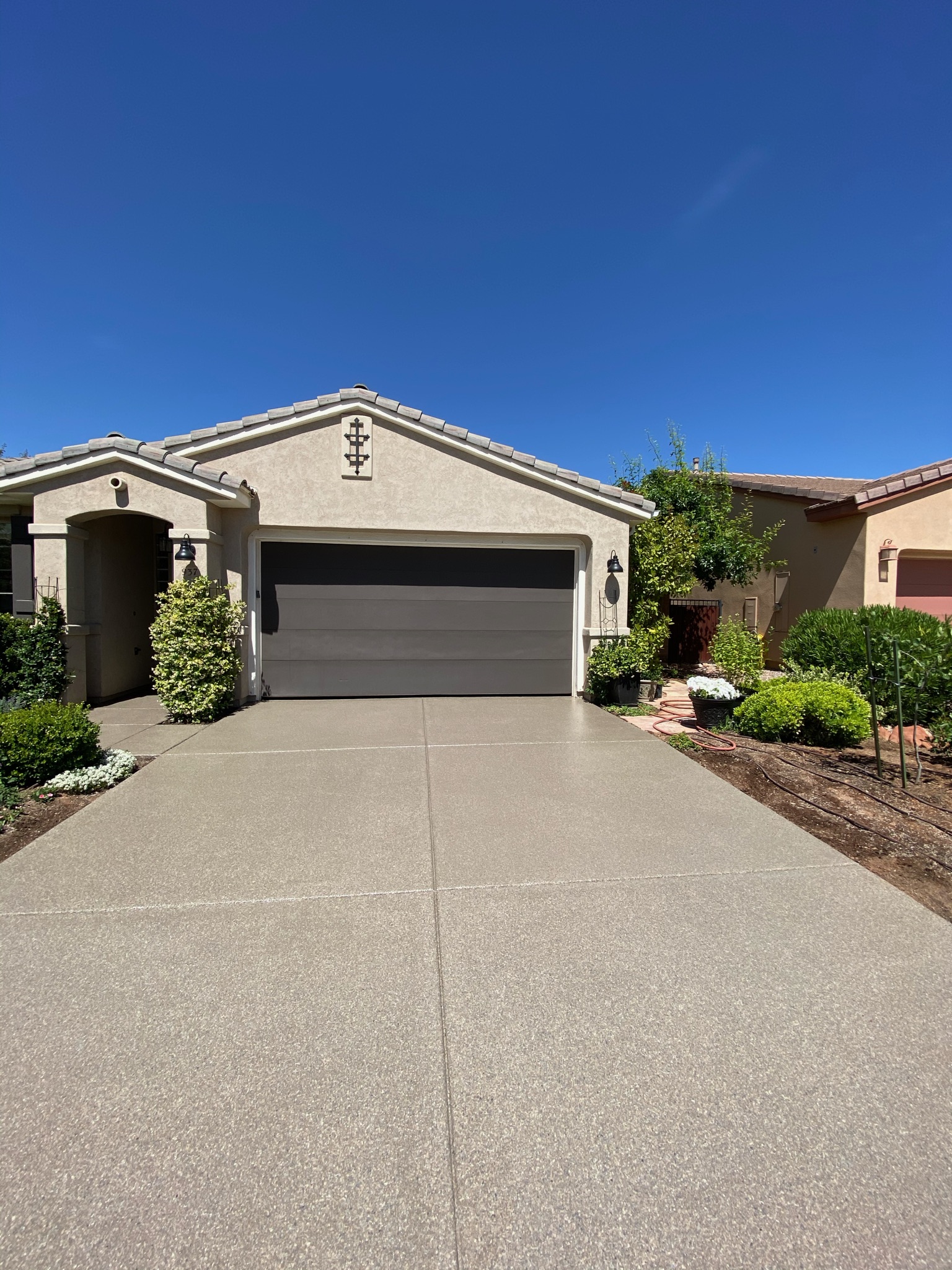 Tan speckle driveway coating with landscaped curb appeal - Sparks Coatings Utah