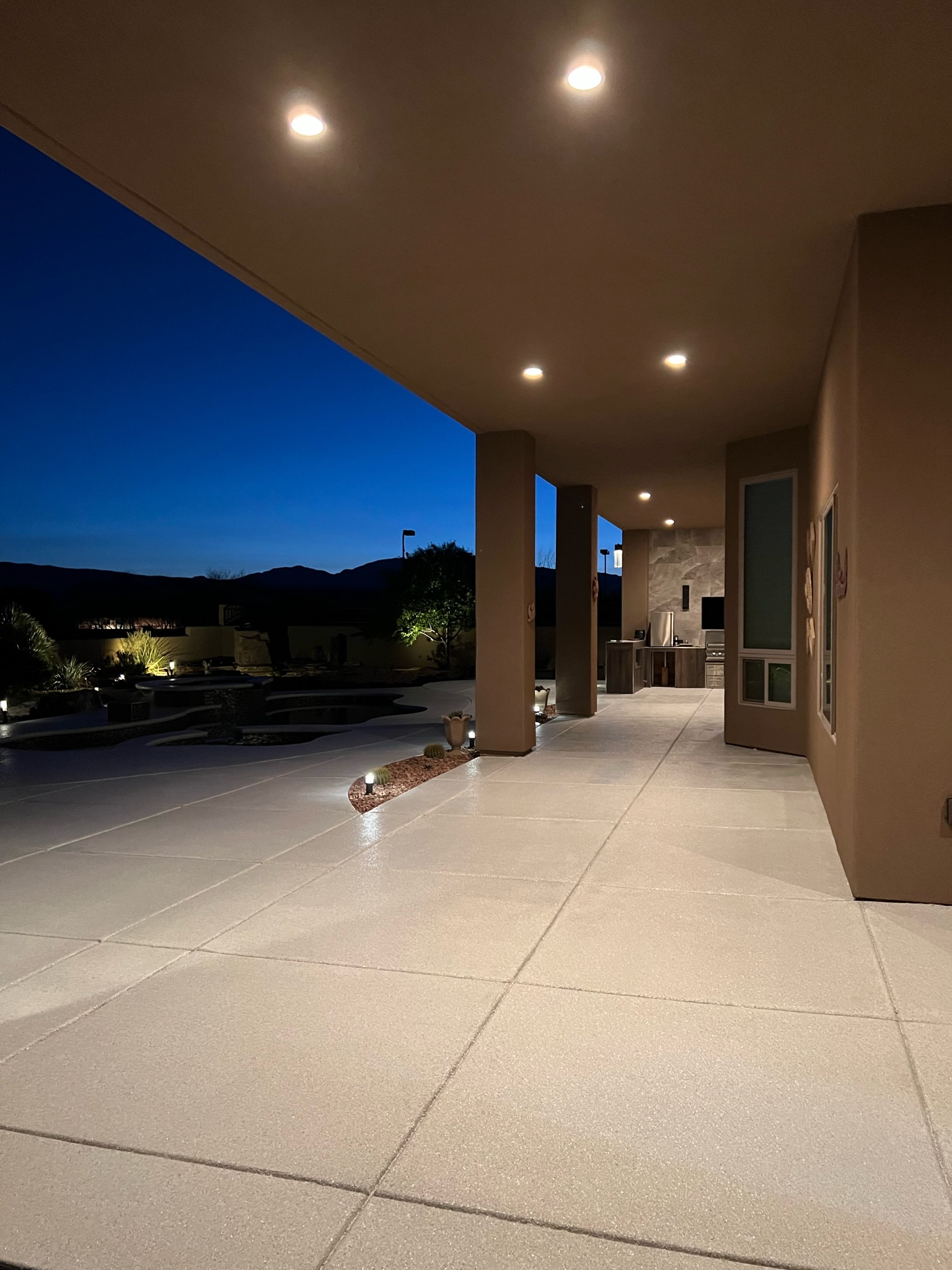 Luxury outdoor patio with floor coating illuminated at night by Sparks Coatings