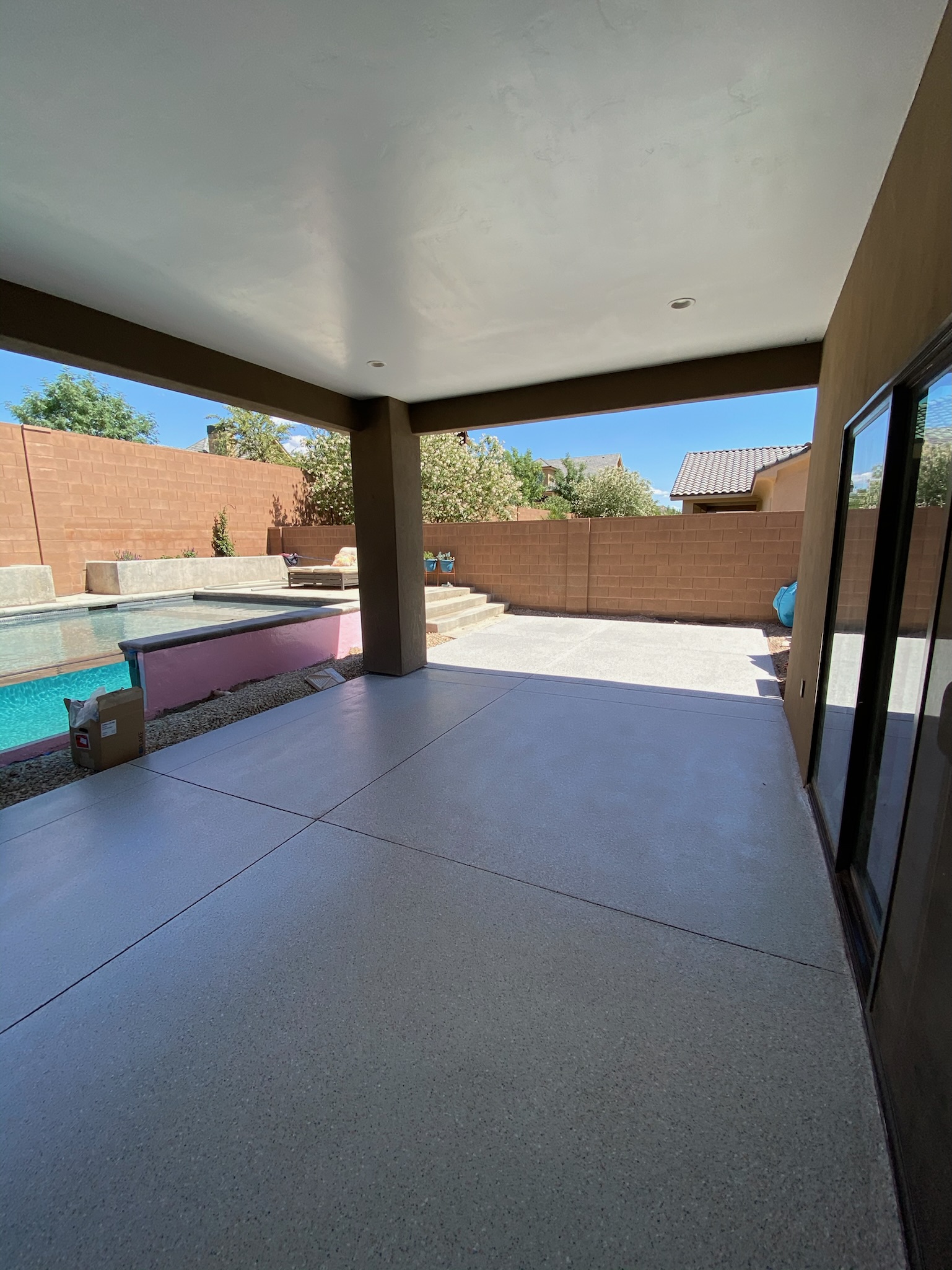 Covered patio with gray professional coating overlooking pool Utah